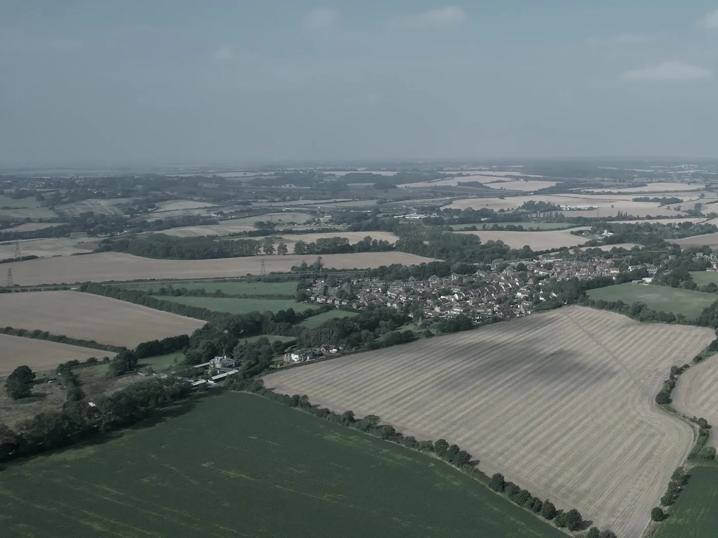 Aerial view of farmland and hedgerows at the edge of a settlement in North West England